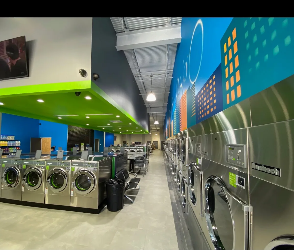 Clean WASH MAXX laundromat interior with rows of stainless steel washers and dryers